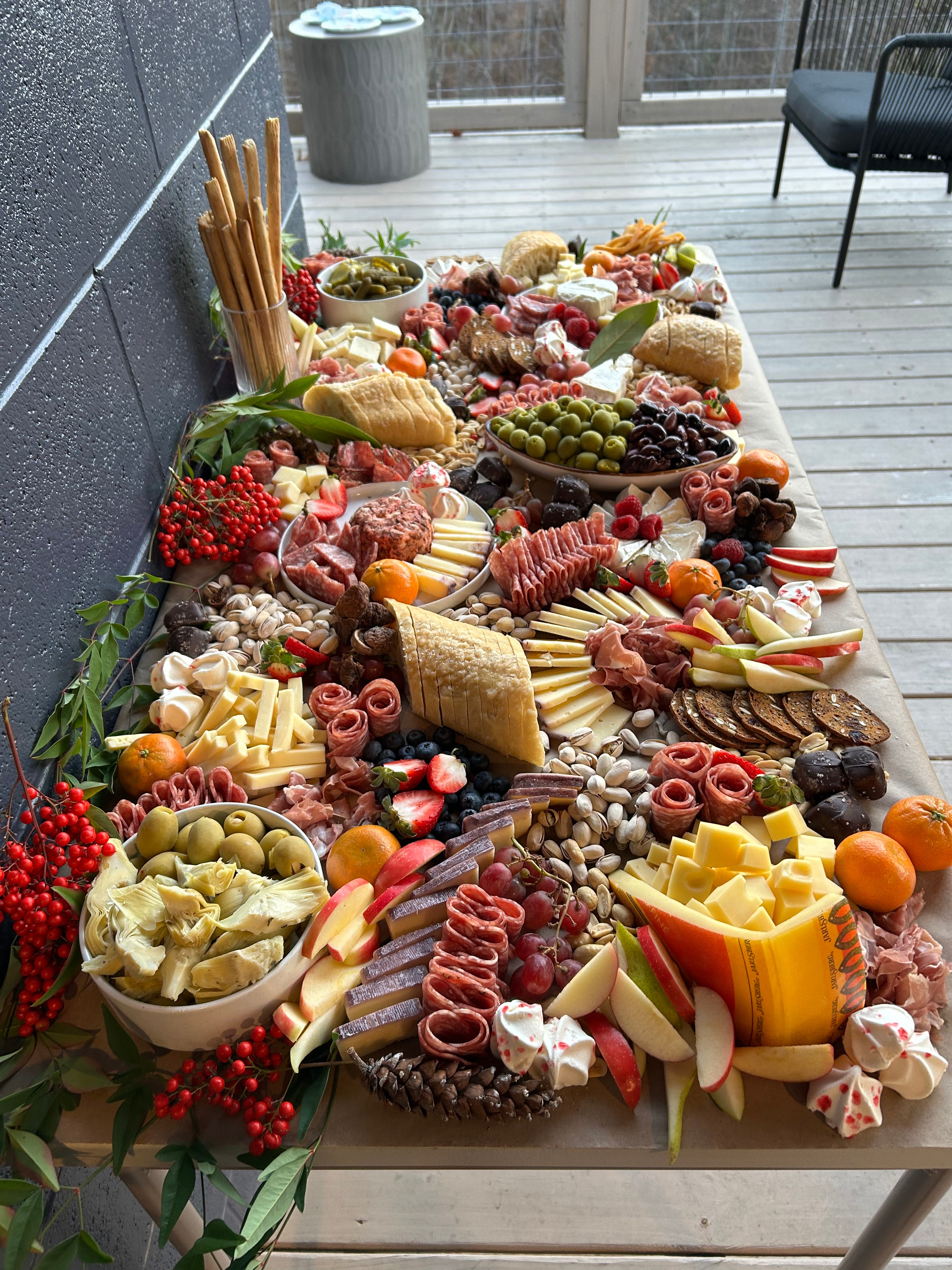 Large outdoor charcuterie tablescape with meats, cheeses, and fruits