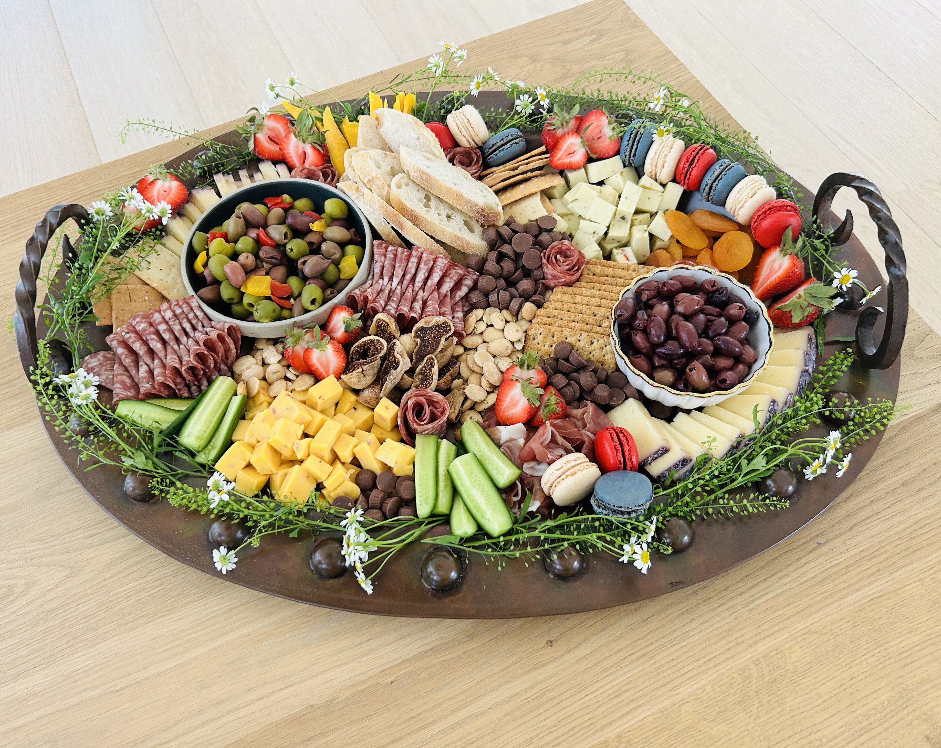 Round wooden charcuterie board with meats, cheeses, and macarons